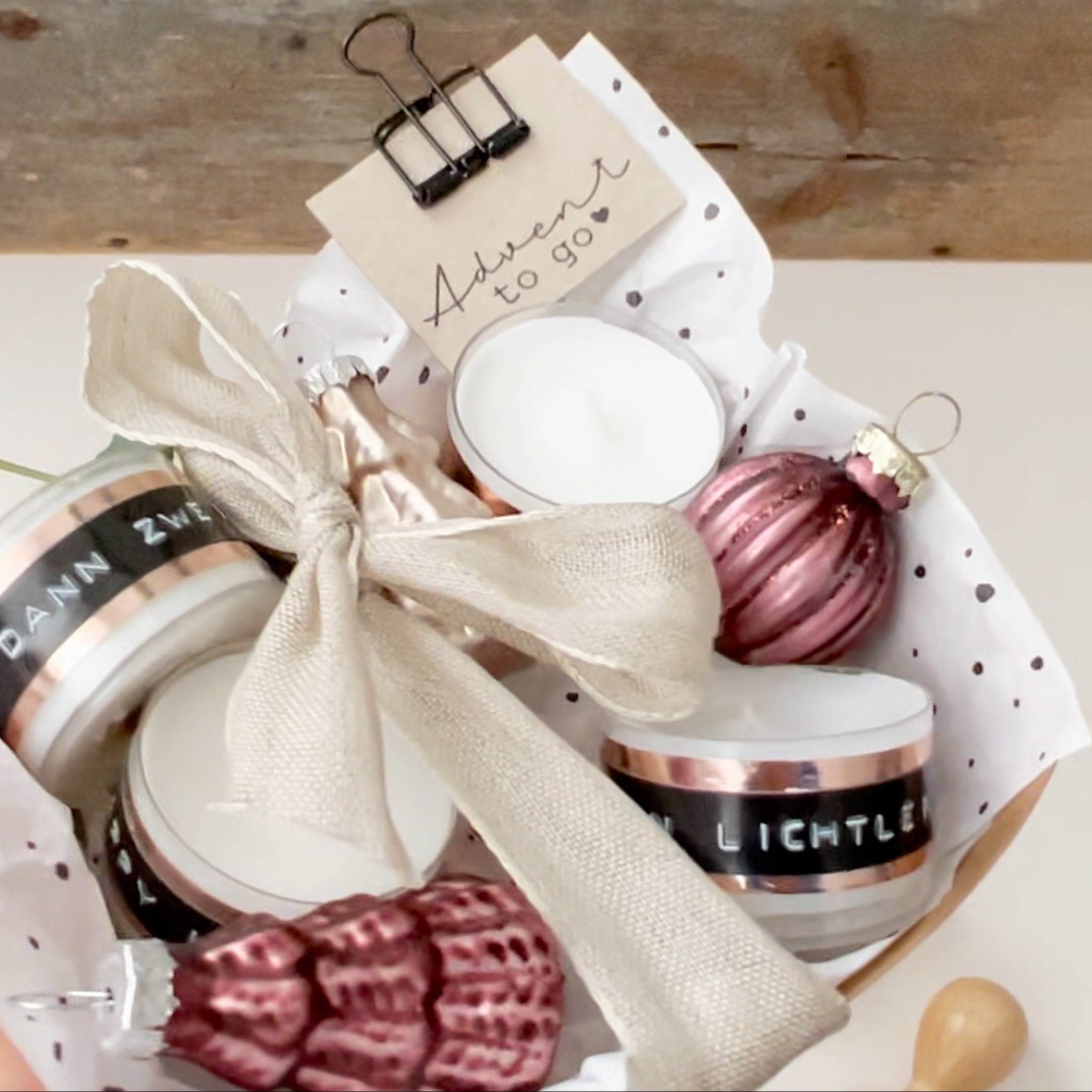 Kleine Box aus Pappe, gefüllt mit 4 Teelichtern, kleinen Weihnachtskugeln auf Seidenpapier und einem Papieranhänger - bestempelt mit "Advent to go"